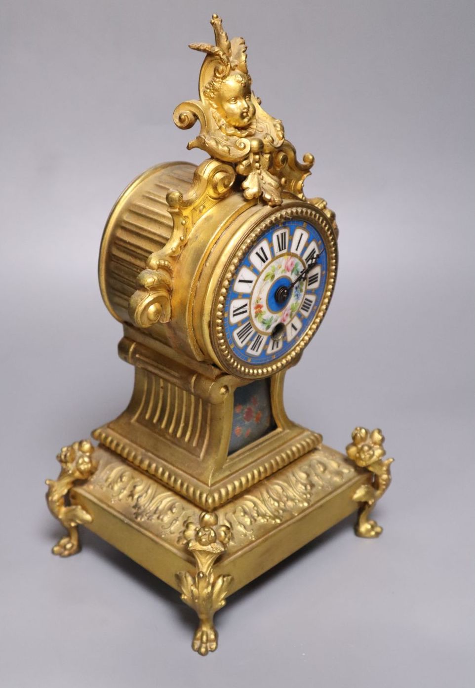 A 19th century French gilt metal mantel timepiece, with ceramic dial, pendulum and key, 31cm